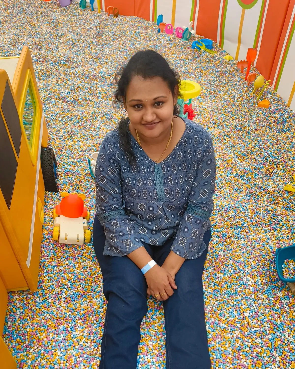 Jeni, creator of Coloring Jar, smiling in a colorful kids' play area